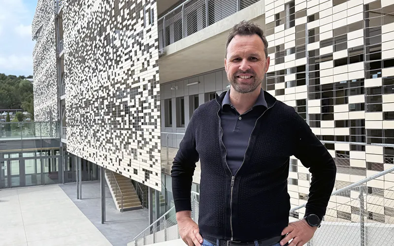 Emmanuel Kot souriant qui se tient devant des bureaux