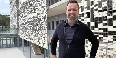 Emmanuel Kot souriant qui se tient devant des bureaux